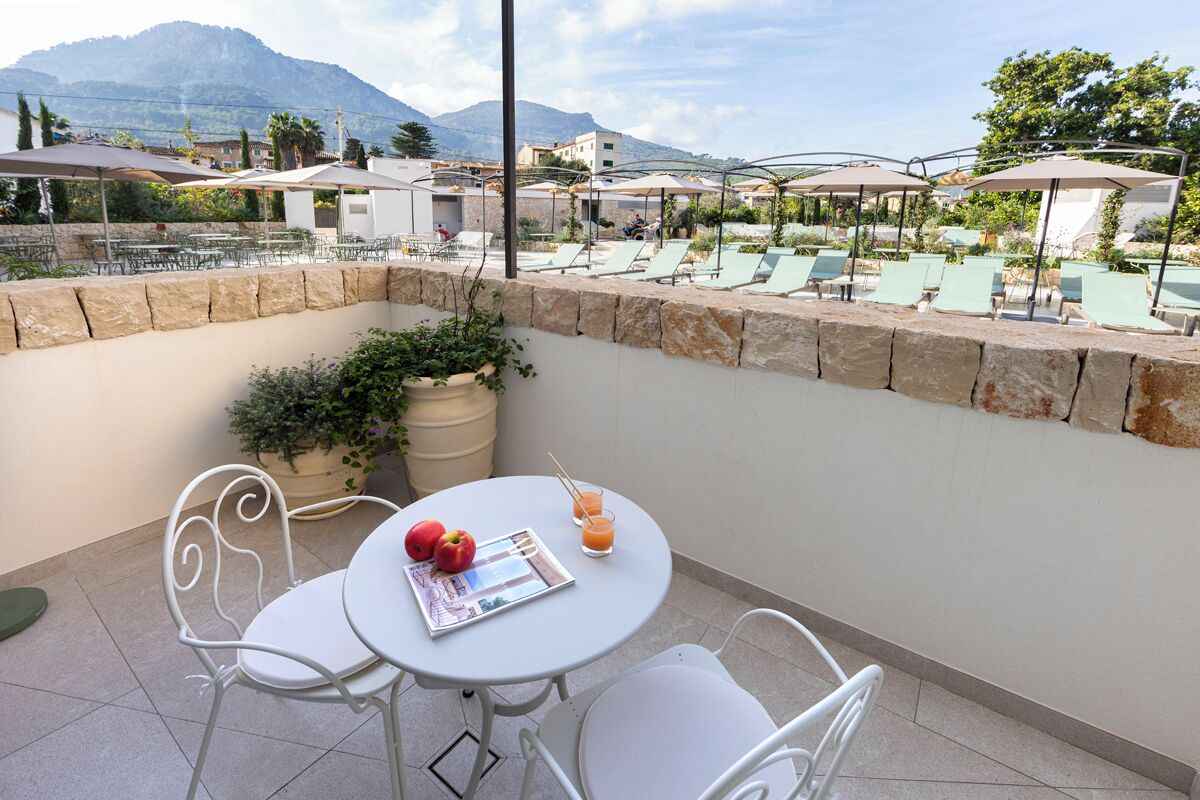 A terrace with stone walls, outdoor seating, and umbrellas.