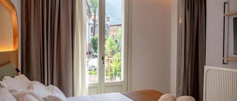 A hotel room with a bed, a view of the outdoors, and a window with curtains.