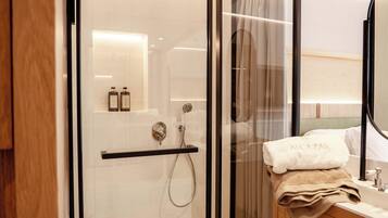 Un bagno moderno con cabina doccia in vetro, un mobile lavabo con specchio e un portasciugamani con un asciugamano piegato.