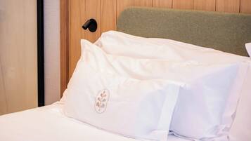 Una cama con ropa blanca y una almohada con diseño floral.