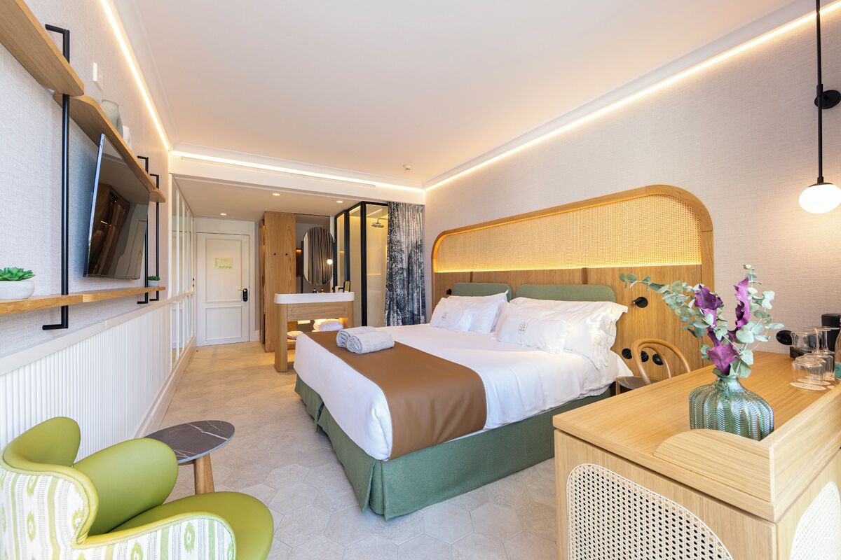 Een moderne hotelkamer met een groot bed, een bureau, een stoel en een televisie aan de muur.