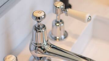 Un baño con grifo cromado, un espejo y dispensador de jabón.