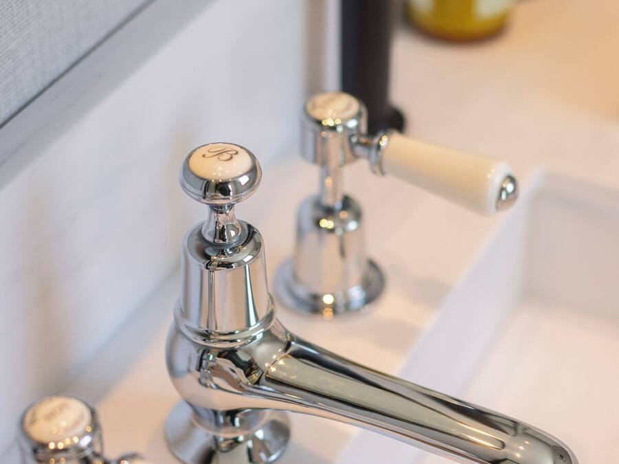 Un baño con grifo cromado, un espejo y dispensador de jabón.