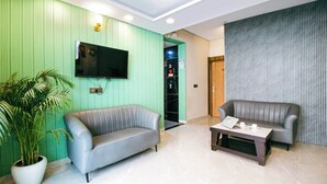 A modern living room with two sofas, a coffee table, and a television. - Treebo Elite Corporate, Sector 62 (New Delhi)