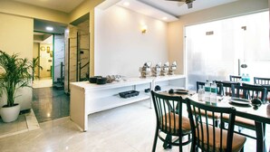 A modern dining area with a white buffet counter, black chairs, and a ceiling fan. - Treebo Elite Corporate, Sector 62 (New Delhi)