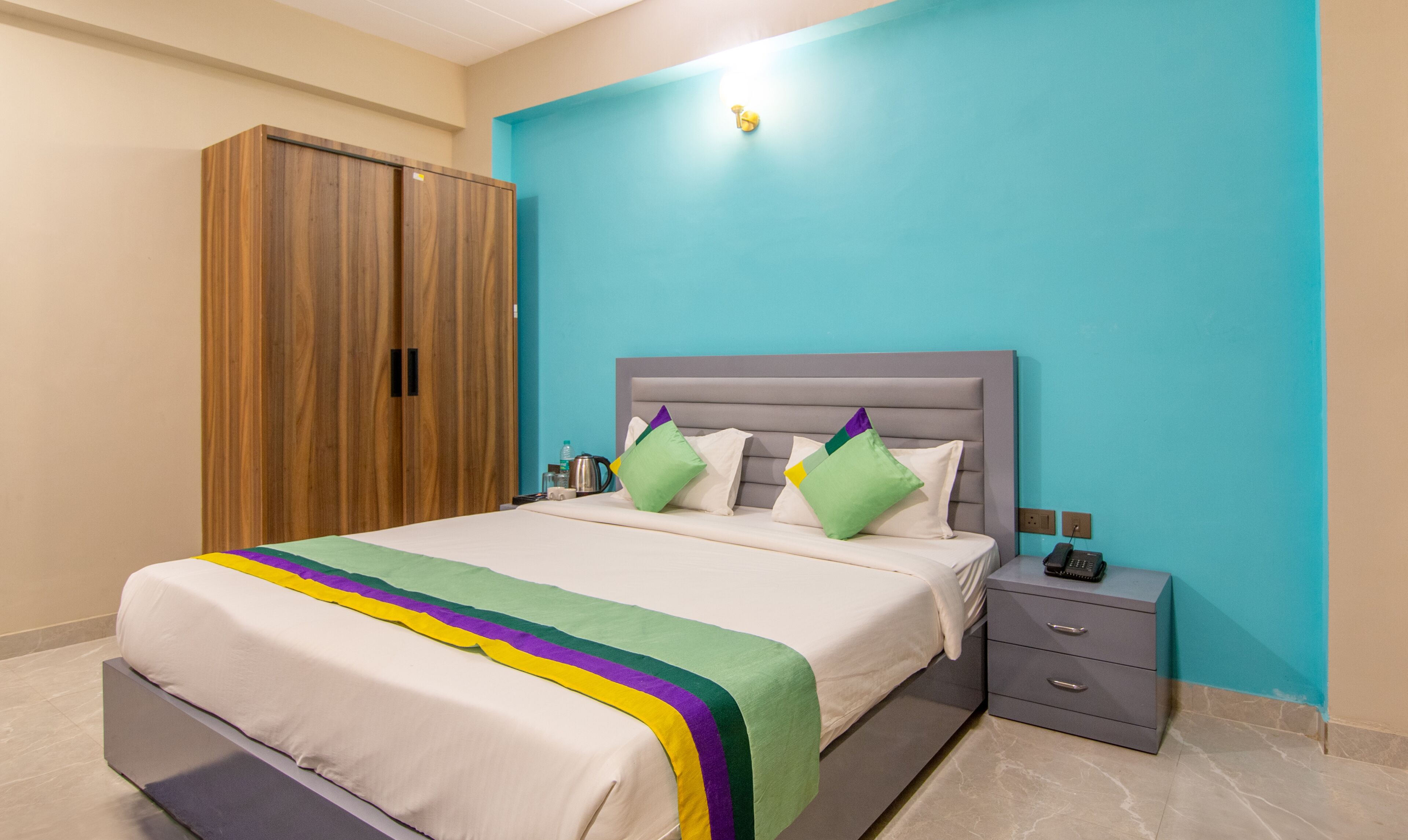 Une chambre à coucher comprenant un lit, une table de chevet, une armoire et un luminaire fixé au mur.