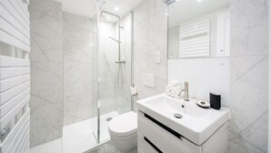 A modern bathroom with a glass shower enclosure, a white toilet, and a vanity with a sink and mirror. - Urban Chic - Acre (London)