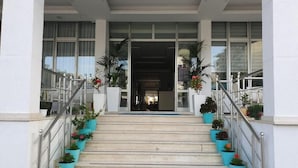 A staircase leading to a building entrance with potted plants on both sides. - Perandor Beach Hotel (Durrës)