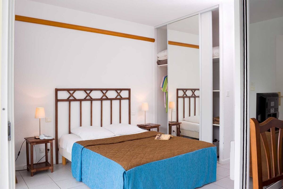 A bedroom with a bed, bedside tables, a mirror, and a wardrobe.
