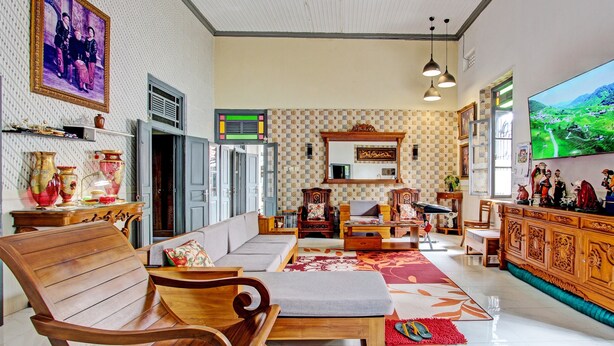 Un salón amplio con sofá, sillas de madera, televisor y un ventanal grande.