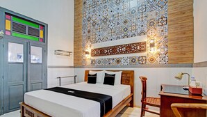Un dormitorio con cama, escritorio de madera y pared con baldosas estampadas.