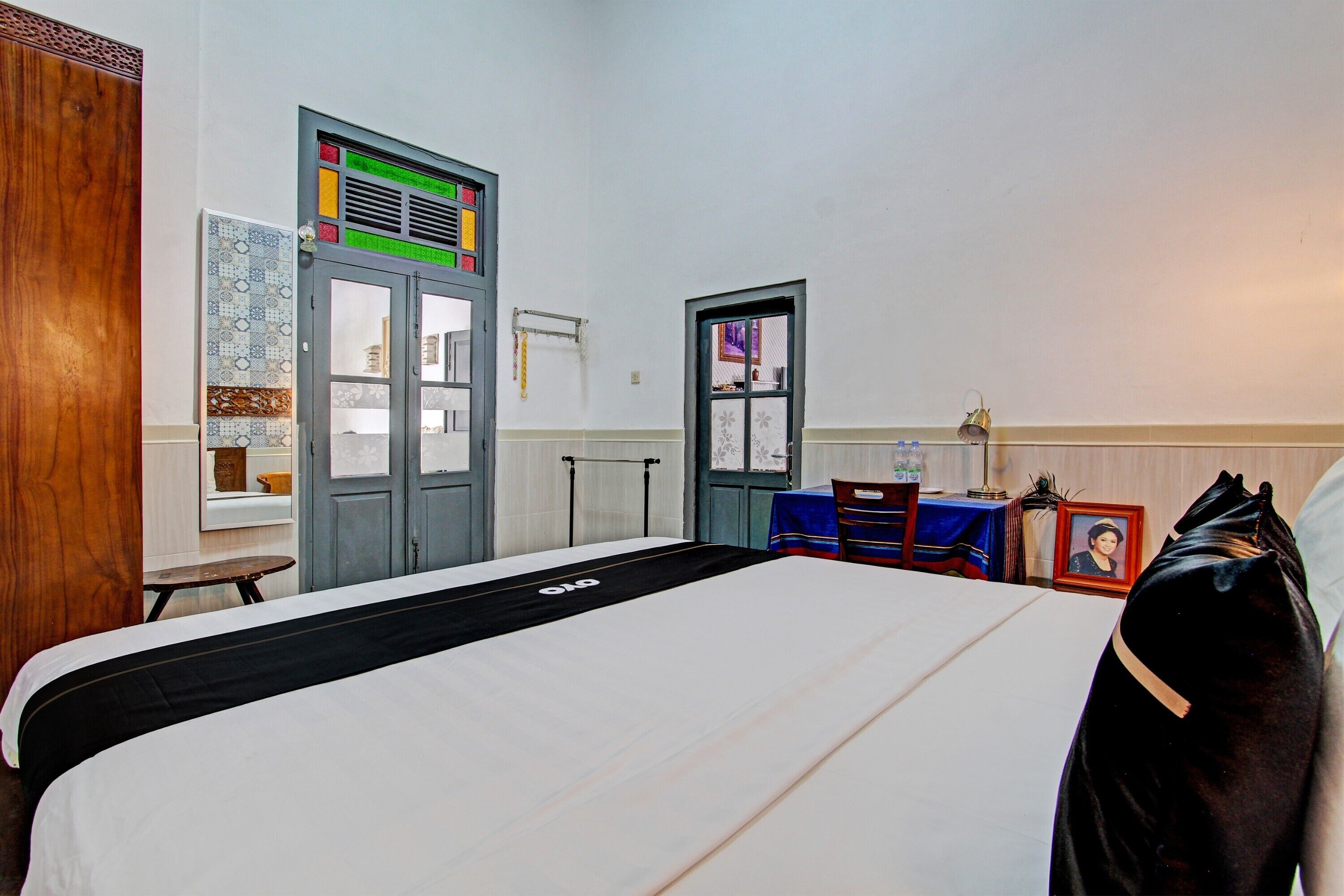 Quarto de hotel com cama grande, guarda-roupa, secretária e janela.