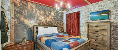 A room with a wooden bed, a stone wall, a red ceiling, a chandelier, a wooden dresser, and a painting of a beach.