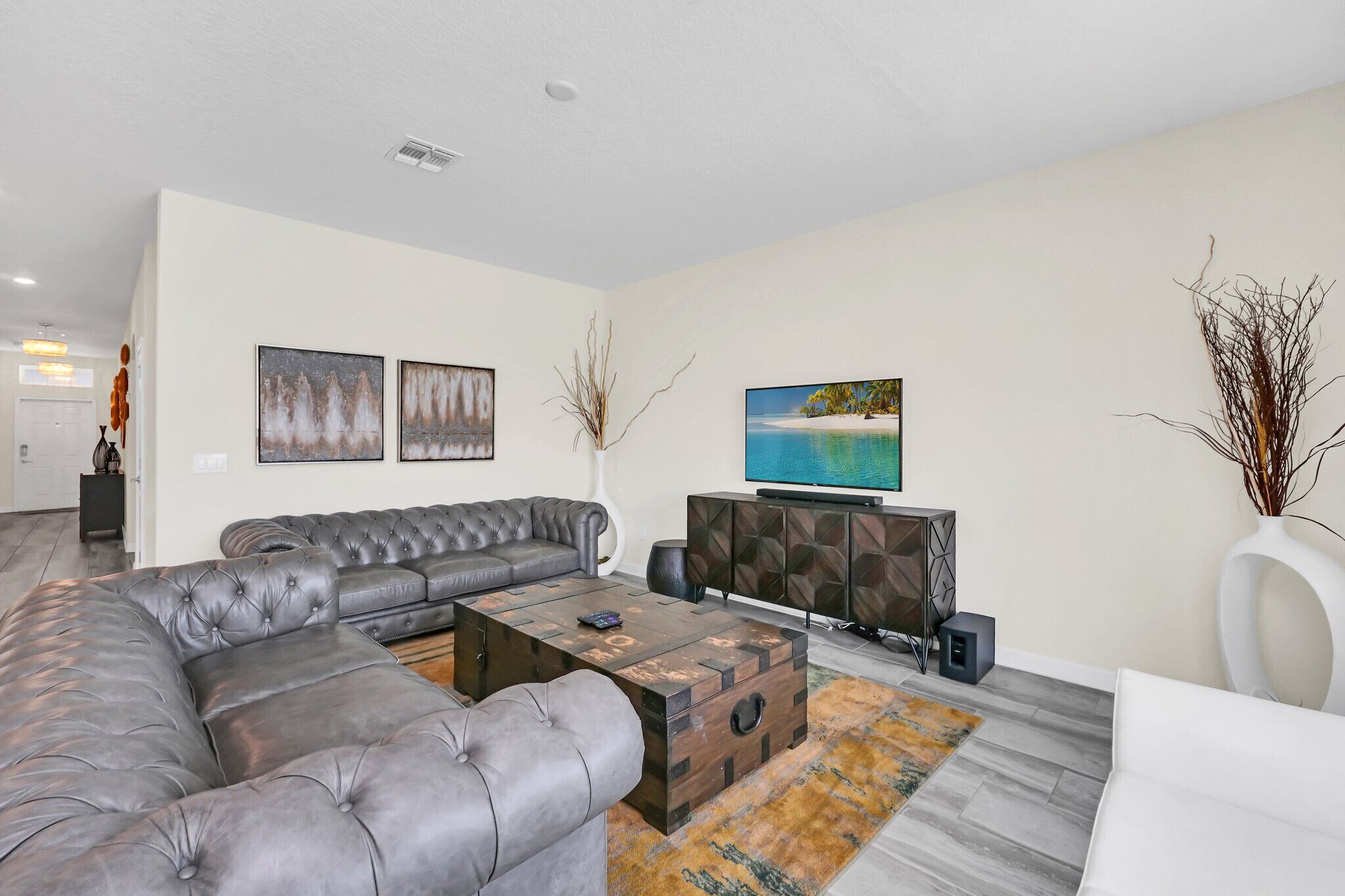 A modern living room with a grey sectional sofa, a wooden coffee table, a flat-screen TV, and a decorative cabinet.