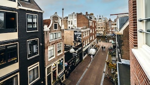 Une rue étroite bordée de bâtiments historiques, dont un immeuble noir portant une enseigne indiquant « Bourbon Street » et un immeuble blanc avec une enseigne indiquant « Live Rhythm ».