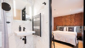 Une salle de bain moderne avec un lavabo en marbre, un porte-serviettes et une cabine de douche en verre.