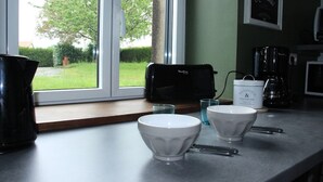 A kitchen counter with two white bowls, a black coffee maker, and a coffee pot.