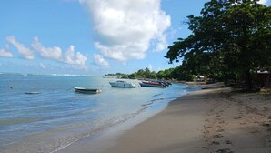 A beach with boats anchored near the shore, a sandy beach, and a clear sky. - Chez Valerie ET Pascal (Tartane)