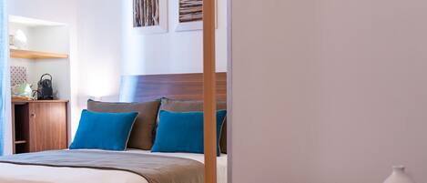 A modern hotel room with a large bed, wooden headboard, and a desk with a lamp.
