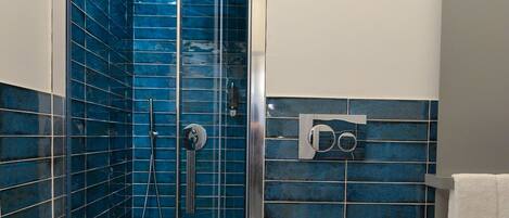 A bathroom with a glass-enclosed shower, a toilet, and a sink.