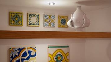 Een kamer met een houten vloer, een witte tafellamp en vier ingelijste kunstwerken aan de muur.