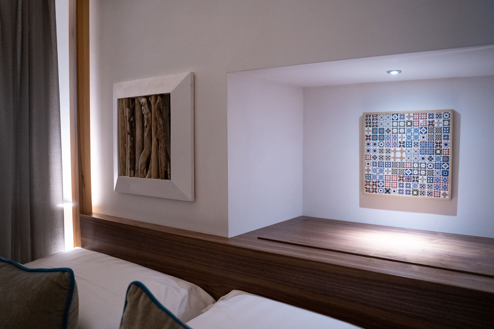 Une chambre d’hôtel avec une tête de lit en bois, une œuvre d’art encadrée et un décor mural composé de carreaux.