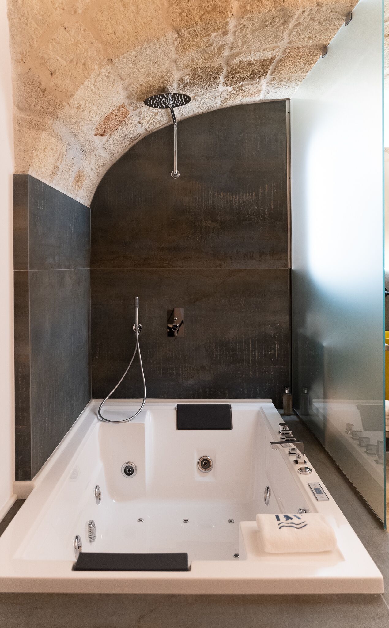 A modern bathroom with a large bathtub, a showerhead, and a glass-enclosed shower area.