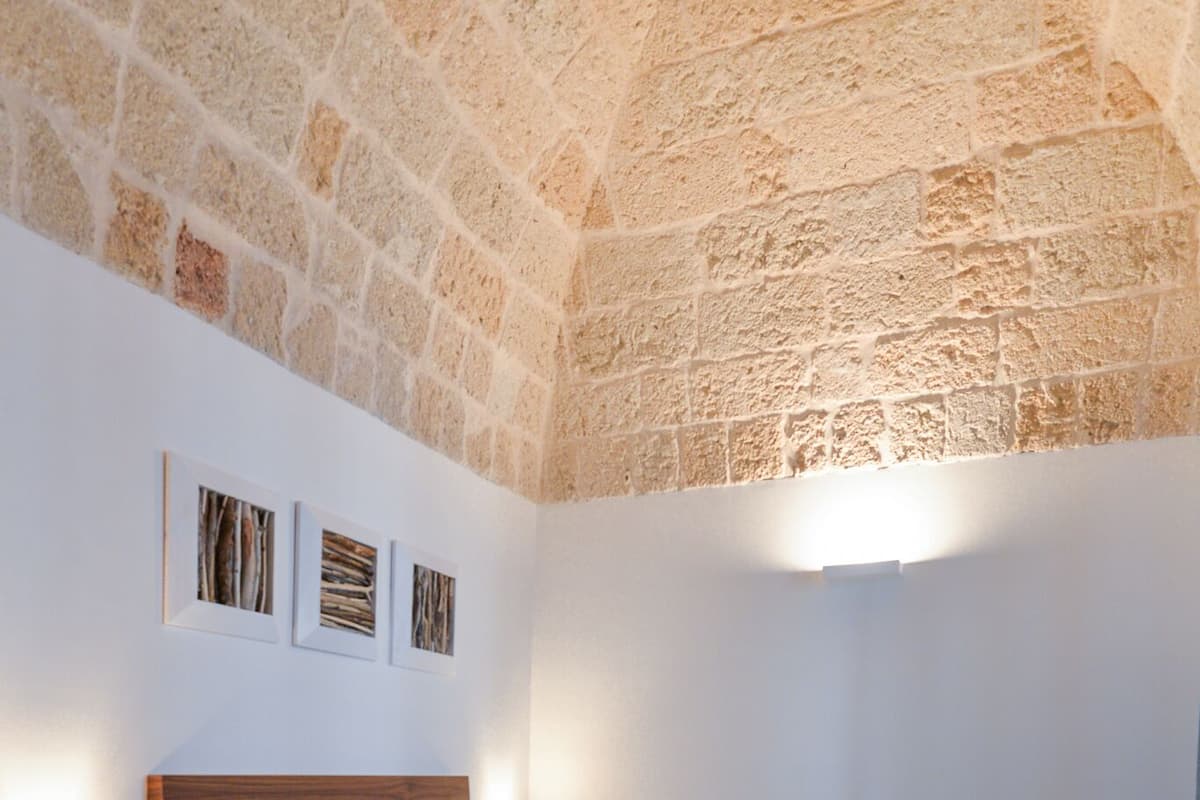 Une chambre avec un plafond en pierre, un cadre de lit en bois et une table de chevet.