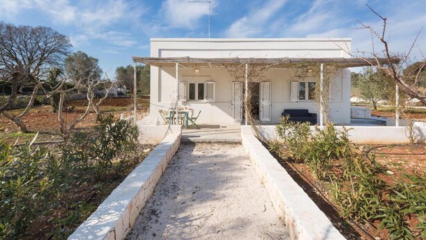 A modern white building with a covered patio, a gravel pathway, and surrounding vegetation. - 805 La Murreddina by Barbarhouse (Ostuni)