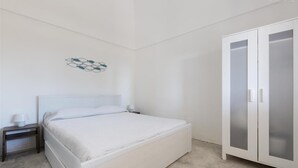 A bedroom with a bed, a nightstand, a wall-mounted light, and a wardrobe. - 805 La Murreddina by Barbarhouse (Ostuni)