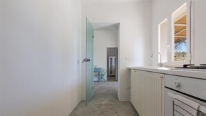 A narrow hallway leading to a kitchen with white cabinets and a window. - 805 La Murreddina by Barbarhouse (Ostuni)