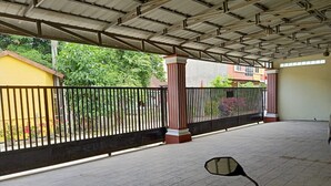 A covered outdoor area with a tiled floor, a black metal fence, and a motorcycle parked in the foreground. - Hotel O Syukur 07 Syariah (Medan)