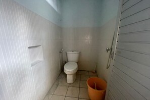 A small, compact bathroom with a toilet, bidet, and a bucket.