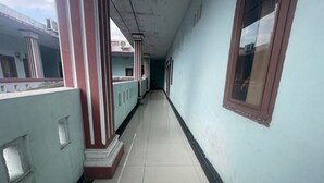 A corridor with a tiled floor, light blue walls, and a window on the right. - Hotel O Syukur 07 Syariah (Medan)