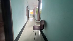 A long, narrow hallway with a single chair in the center, flanked by light green walls and a white floor. - Hotel O Syukur 07 Syariah (Medan)