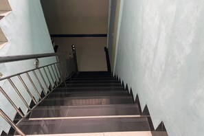 A staircase with metal railings and dark, reflective steps leading to a landing. - Hotel O Syukur 07 Syariah (Medan)