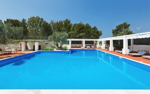 A swimming pool with lounge chairs and a covered seating area. - 836 Masseria Colosso - Pajara (Patu)