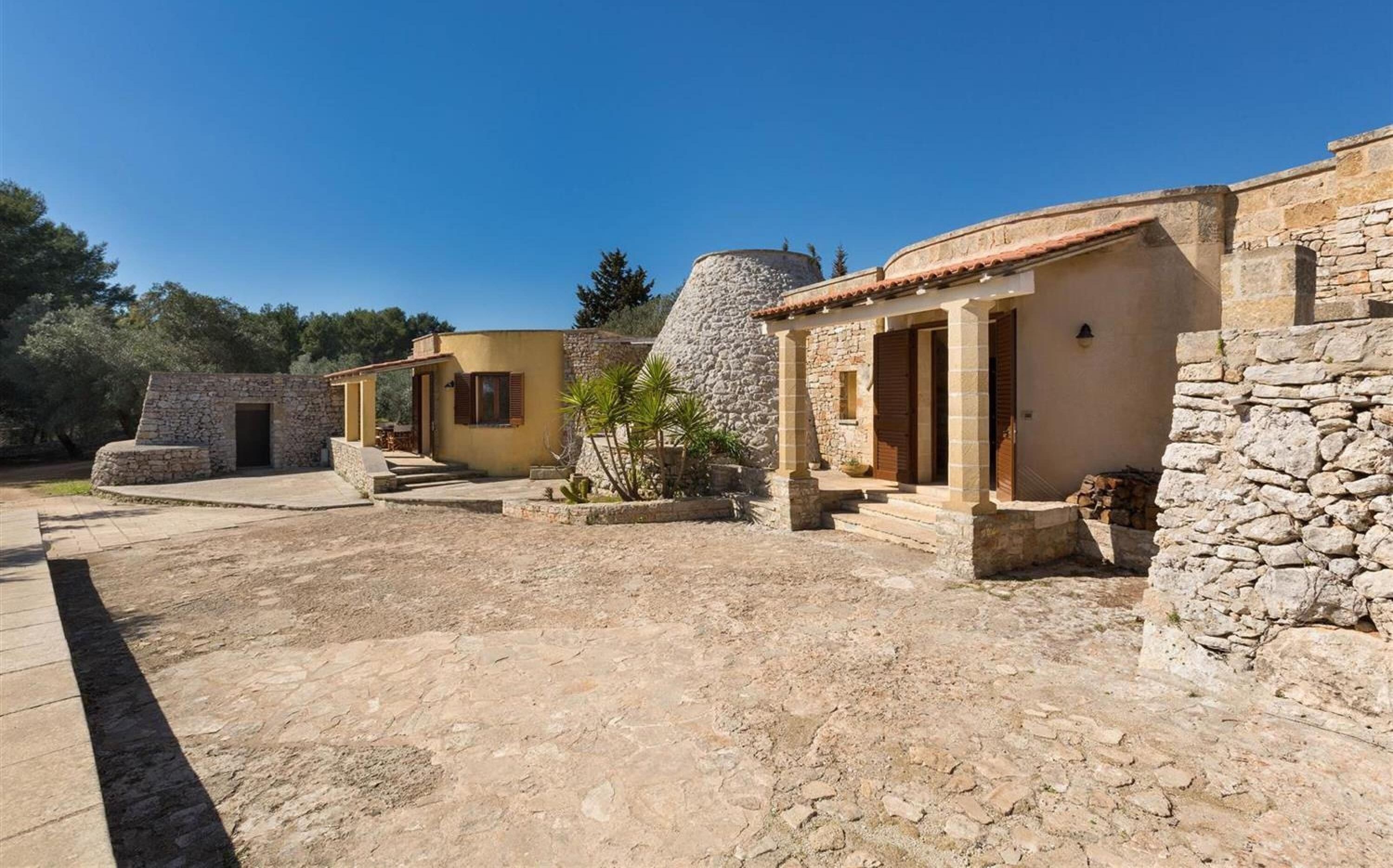 Un patio con edificios de piedra, una torre de piedra y un camino empedrado.