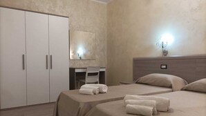 Ein Hotelzimmer mit zwei Betten, einem Schreibtisch, einem Stuhl und einem Kleiderschrank.