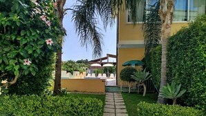 Ein Weg zu einem Gebäude mit Außenbestuhlung und einem überdachten Bereich.