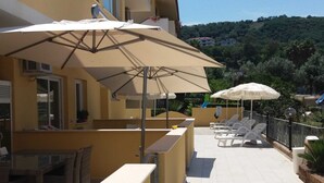 Eine Terrasse mit Sitzgelegenheiten, Sonnenschirmen und Blick auf eine Hügelterrasse.