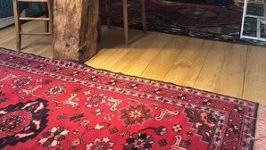 A room with a large wooden beam structure, a bed with a green bedspread, a red patterned rug, and a chair. - Pavillon de Chasse, Gîte 2/4 Pers (Blanzay)
