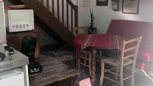A cozy kitchen with a wooden staircase, a dining area with a red tablecloth, and various wall decorations. - Pavillon de Chasse, Gîte 2/4 Pers (Blanzay)