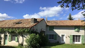 A two-story house with a tiled roof and green shutters, surrounded by a well-maintained lawn. - Pavillon de Chasse, Gîte 2/4 Pers (Blanzay)
