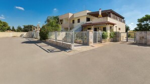 A two-story residential building with a gated entrance, a staircase leading to the upper floor, and a clear sky. - 984 Appartamento Solaris (Nardò)