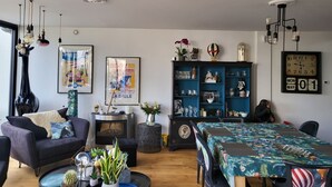 Een moderne woonkamer met een open haard, een eethoek met een tafel, en een boekenkast.