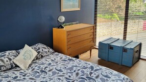 Een slaapkamer met een bed, een kaptafel en een ingelijst schilderij aan de muur.