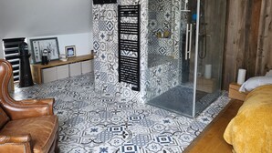 Een moderne badkamer met patroon betegelde vloeren, een douchecabine van glas en een houten wastafelmeubel.