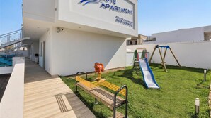 An outdoor area with a sign for Absolute Apartment, a playground with a slide, and a bench. - 1049 Absolute - Bilo Piano Terra (Porto Cesareo)