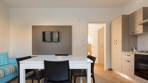 A modern kitchen with wooden cabinets, a white countertop, and a built-in oven. - 1049 Absolute - Bilo Piano Terra (Porto Cesareo)